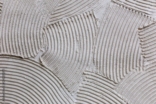 Abstract plaster texture closeup with decorative lines. Plaster curved lines create artistic abstract pattern. Concept of modern plaster textured surface for stylish interior and creative decor