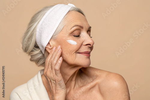 charming elderly woman apply cream face healthy skin isolated on beige color background