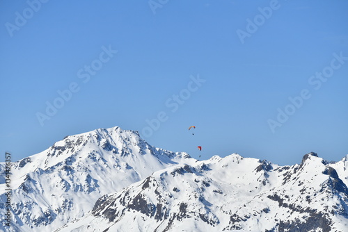 Paragliders over the snowy French alps by winter