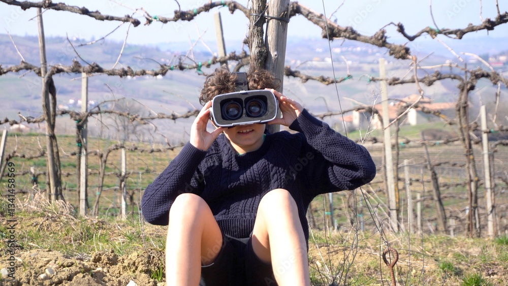 10 year old boy with 3d AI virtual reality headset viewer in nature immerses himself in an immersive visual experience with reality augmented by artificial intelligence
