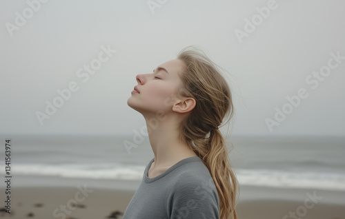 young woman on the beach. A woman standing with her eyes closed and her head tilted back,  calm atmosphere.