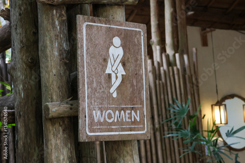 selective focus Wooden sign for women's restroom written in white. A cafe restroom in a deep forest decorated in a shady, natural style with space for text.