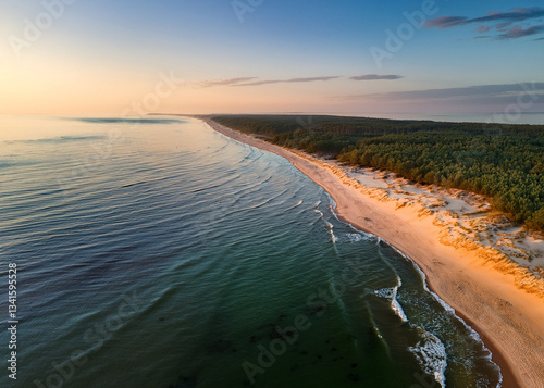 A stunning Curonian Spit beach at sunrise, with turquoise waters, soft sand, and gentle waves lapping the shore, captured from above.