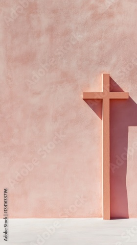 Religious cross on a pink wall, with soft tones. Minimalist cross with delicate details in a concept of spirituality and serenity.