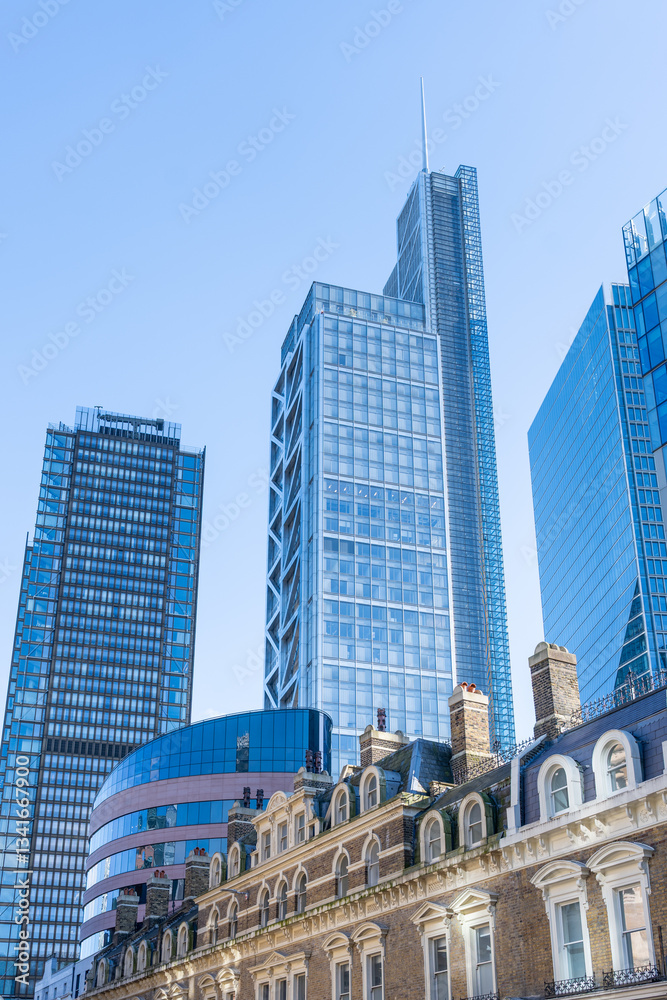 Obraz premium Skyscrapers stand tall against a clear blue sky in the City of London, showcasing modern architecture alongside historic buildings, creating a unique urban landscape.
