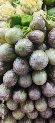 a pile of round, purple-striped eggplants (brinjals) that are fresh and neatly arranged
