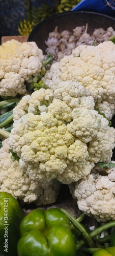 fresh vegetables, including cauliflower, green bell peppers, and garlic. The cauliflower heads are in the center