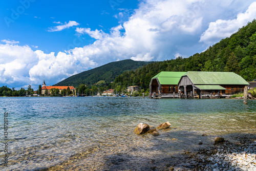 Idyllic panorama view of Tegernsee lake with Bavarian alps and Tegernsee town including St. Quirinus parish church, on a sunny summer day with blue sky cloud, Bavaria, Germany