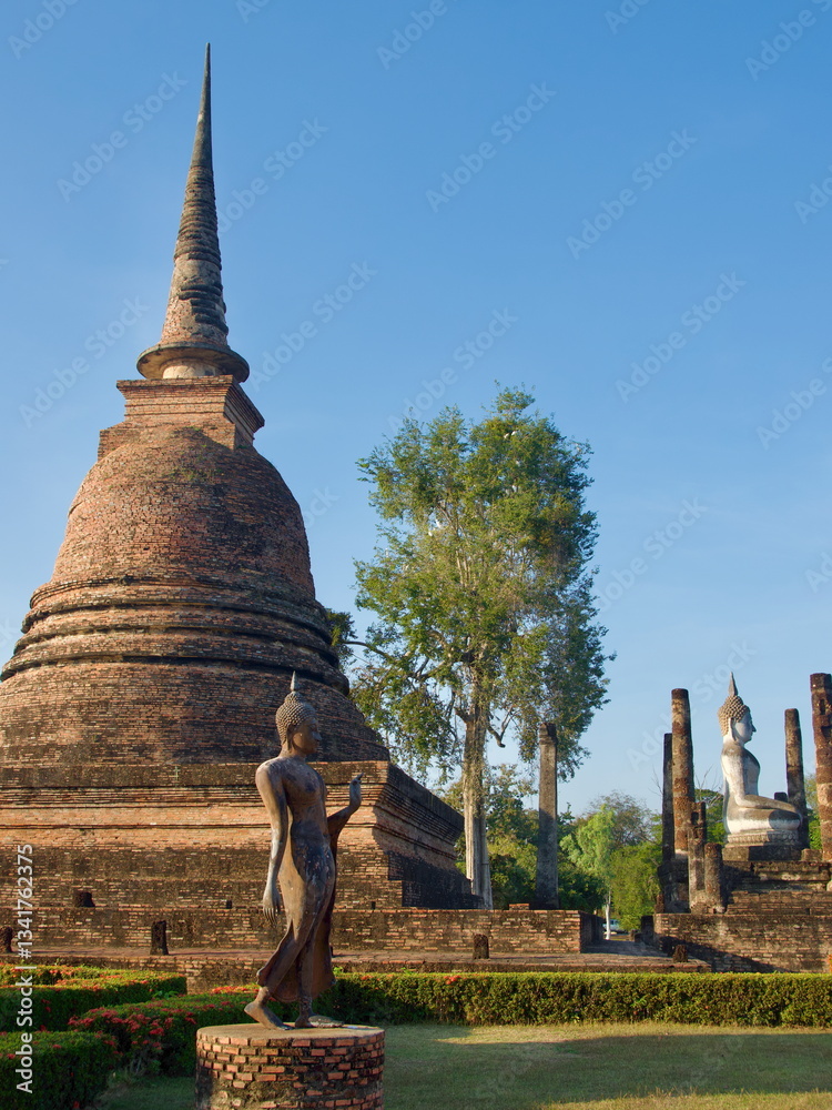 Statues of walking and sitting Buddha in Sukhothai Historical Park in Thailand