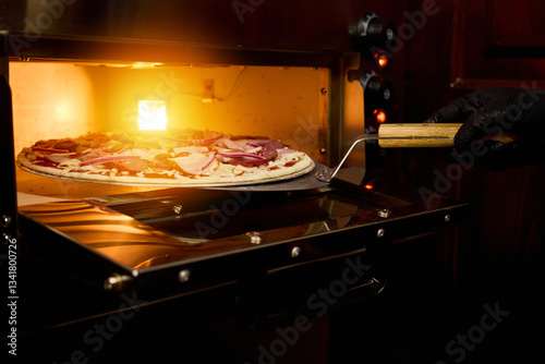 Quadro em tela A chef uses a pizza peel to remove a freshly baked pizza topped with meats and c