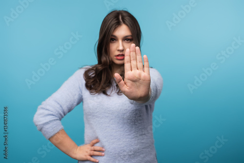 Confident woman extending hand assertively, expressing rejection or denial. Ideal for themes of boundaries, refusal, communication, and assertiveness in professional and personal contexts on vibrant