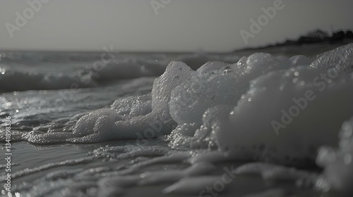 Close-up monochrome view of ocean wave foam, textured, glistening, abstract.