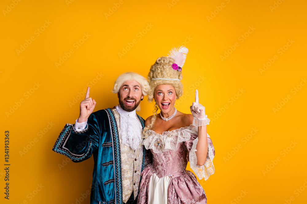 Fototapeta premium Elegant couple in historical costumes posing against a vibrant yellow background for a masquerade or theme party celebration