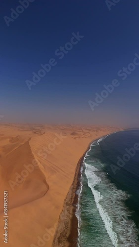 Vertical aerial drone view of Sandwich Harbour, where giant sand dunes meet the Atlantic Ocean. This stunning location is situated near Walvis Bay in the Namib-Naukluft National Park. Namibia, Africa