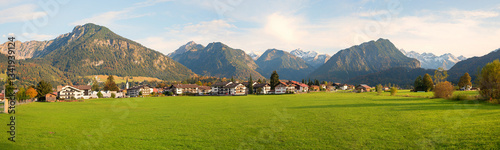 Obraz na płótnie view over green pastures to Oberstdorf tourist resort, allgau alps in autumn w salonie