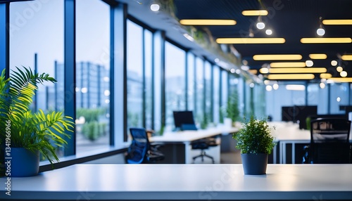 Office Plant on Modern Desk - A small green plant in a yellow pot sits on a white desk in a modern, bright office setting. The background is blurred, showing blue office furniture and windows.