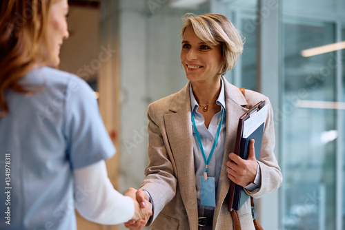 Fotografie Happy businesswoman greeting nurse while meeting in hospital.