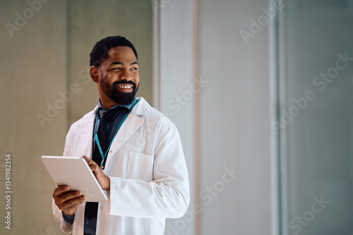 Schilderij op canvas Happy black doctor using touchpad while working at medical clinic