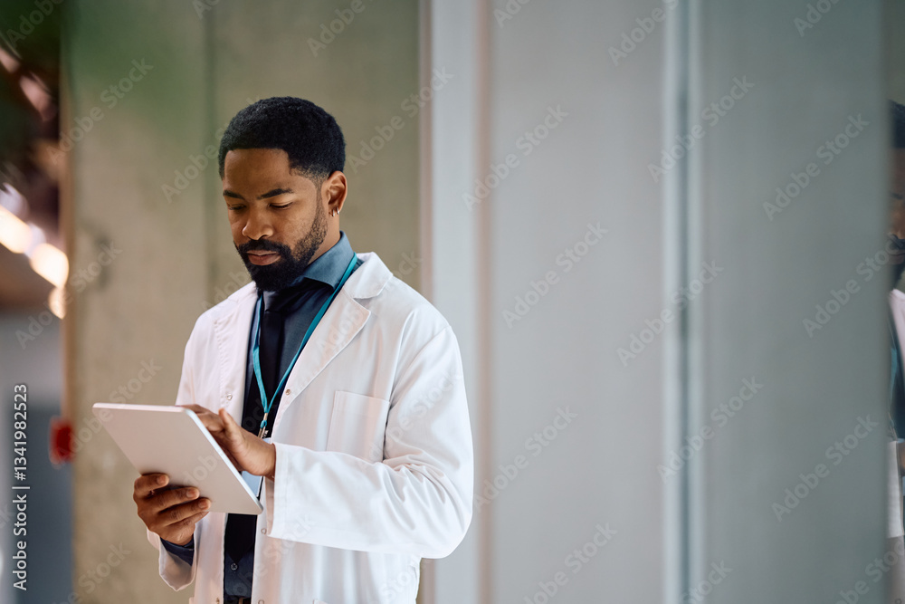 Black doctor working on digital tablet in hospital. Black doctor working on digital tablet in hospital.
