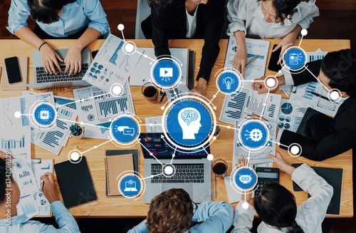 A dynamic office scene showcasing a team engaged in brainstorming and strategizing around AI. Charts and digital devices fuel innovation and collaboration. Amity photo