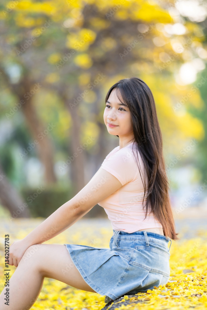 Portrait cute smiles Asian of attractive young teenage girl in Beautiful blooming Yellow Golden Tabebuia Chrysotricha flowers with the park in spring day at Evening background in Thailand.