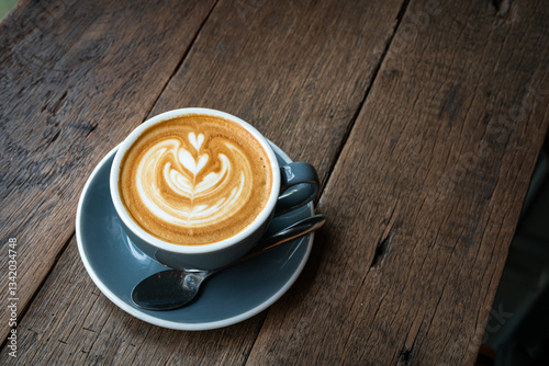 Obraz na płótnie Hot coffee latte with latte art milk foam in cup mug on wood desk on top view. As breakfast In a coffee shop at the cafe,during business work concept,vintage style w salonie