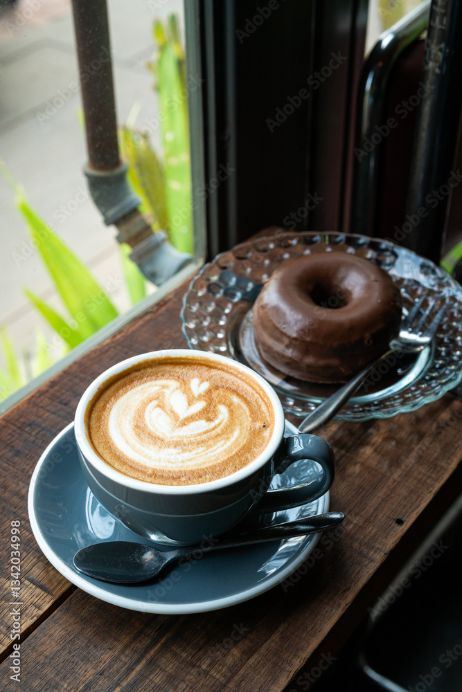 Hot coffee latte with latte art milk foam in cup mug and Homemade chocolate Donut on wood desk on top view. As breakfast In a coffee shop at the cafe,during business work concept,vintage style