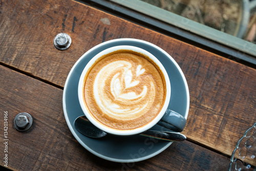 Hot coffee latte with latte art milk foam in cup mug on wood desk on top view. As breakfast In a coffee shop at the cafe,during business work concept,vintage style