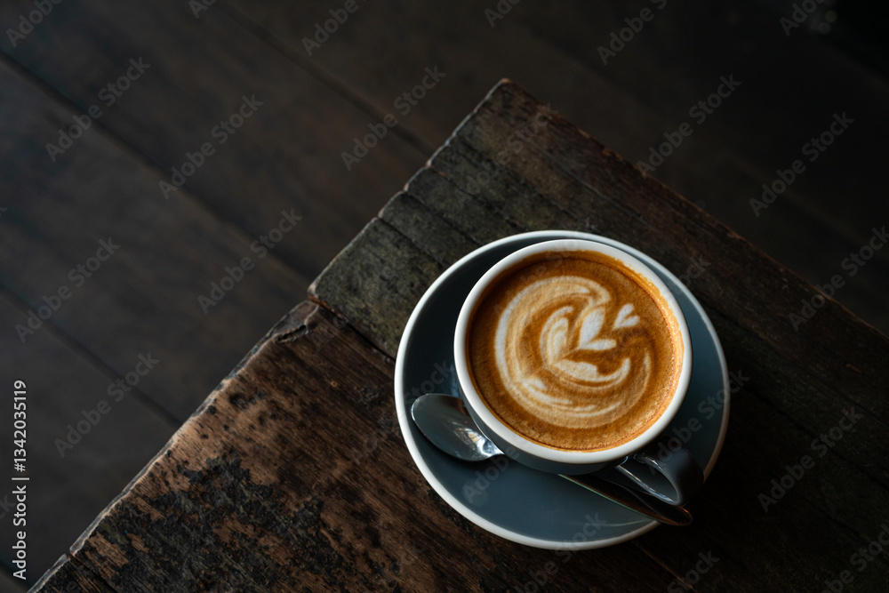 Hot coffee latte with latte art milk foam in cup mug on wood desk on top view. As breakfast In a coffee shop at the cafe,during business work concept,vintage style