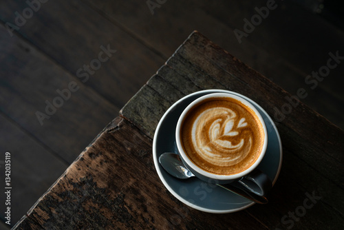 Obraz na płótnie Hot coffee latte with latte art milk foam in cup mug on wood desk on top view. As breakfast In a coffee shop at the cafe,during business work concept,vintage style w salonie