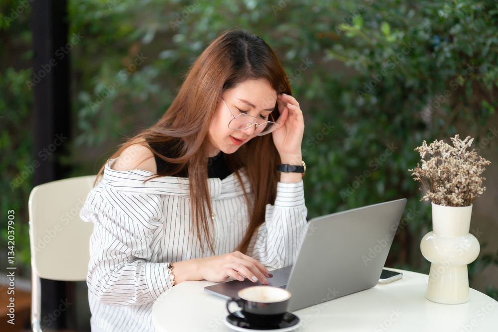 Stressed freelance people business asian female Having Headache While Working Using laptop computer with coffee cup and smartphone at window in coffee shop like the background