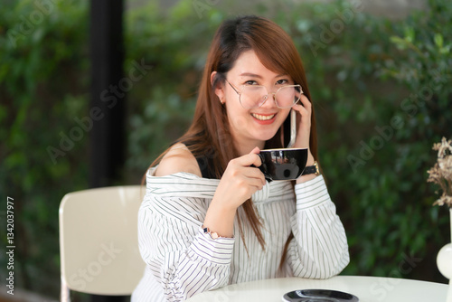 Obraz na płótnie Portrait of beautiful happy Smiling asian woman relaxing and and smartphone sitting in cafe interior in coffee shop background w salonie