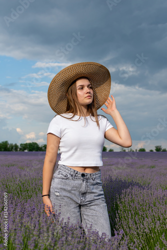A woman in a straw hat stands in a field of purple flowers