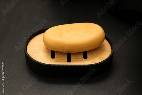 Obraz na plátně A natural brown eco-friendly soap  placed on a wooden soapbox against a black background
