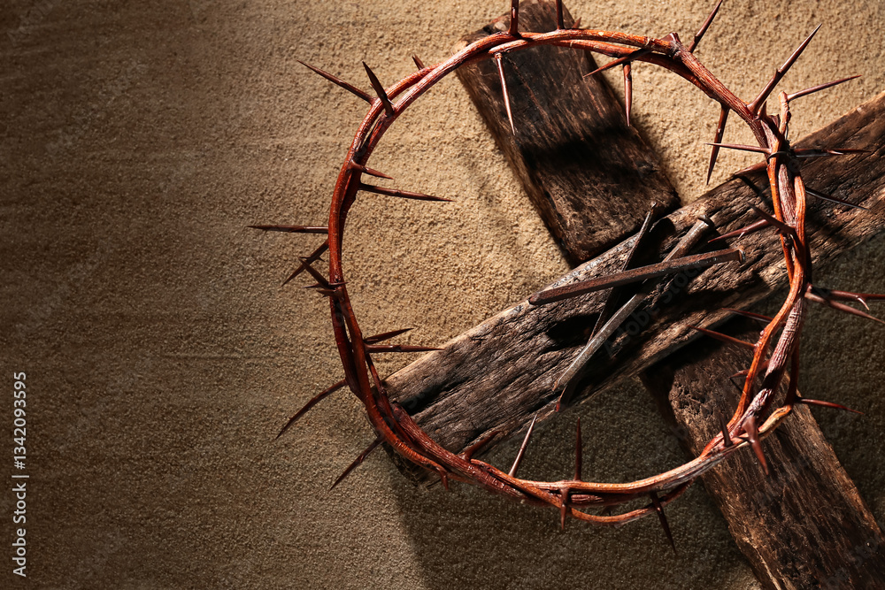 Obraz premium Crown of thorns with wooden cross on sand background