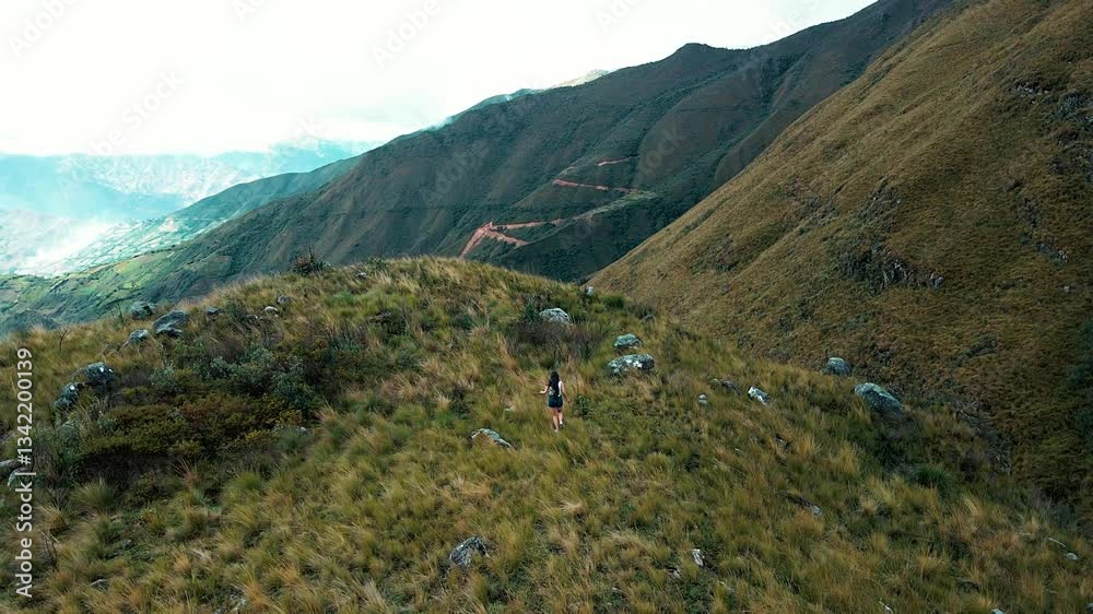 Joven corriendo en la naturaleza entre montañas y paisajes mágicos . Chica en shorts disfrutando el aire libre y el turismo en la montaña.estilo de vida saludable .video drone.