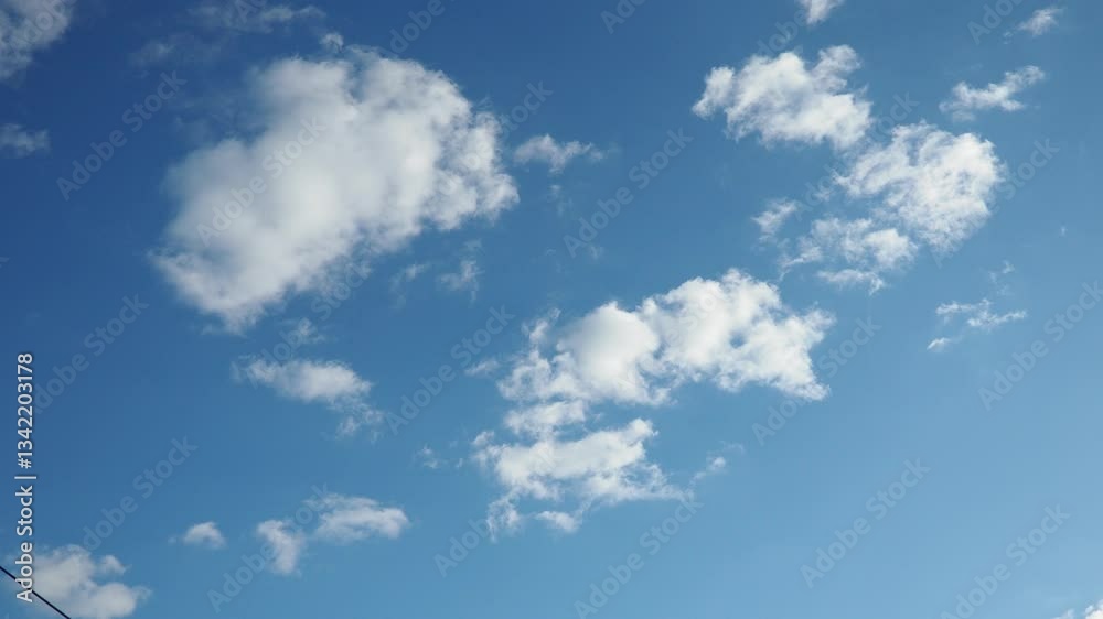 Fluffy white clouds float gracefully against a vibrant blue horizon, creating a serene atmosphere that invites tranquility and reflection during a calm afternoon. Real time, slow motion sky Fluffy white clouds float gracefully against a vibrant blue horizon, creating a serene atmosphere that invites tranquility and reflection during a calm afternoon. Real time, slow motion sky
