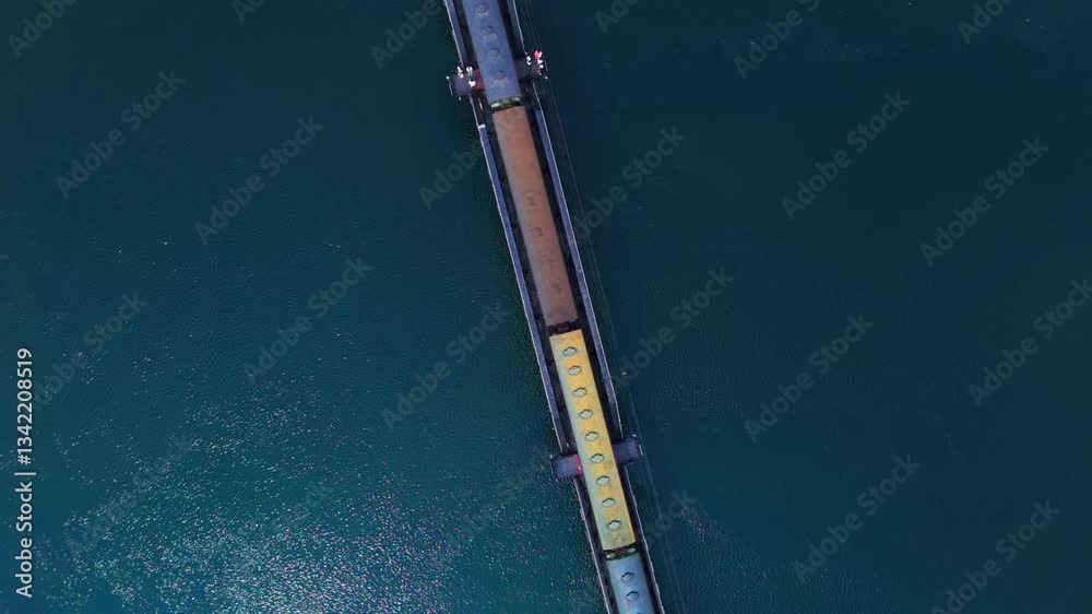 Top view drone shot showing a train passing over the historic World War II bridge over the River Kwai. It is now maintained and usable as a historical tourist attraction in Kanchanaburi, Thailand.