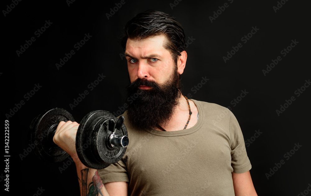 Serious strong man training with dumbbells in sports club. Handsome bearded man lifting dumbbell and doing weightlifting. Athlete man raises dumbbell. Healthy lifestyle and strength exercises at gym. Serious strong man training with dumbbells in sports club. Handsome bearded man lifting dumbbell and doing weightlifting. Athlete man raises dumbbell. Healthy lifestyle and strength exercises at gym.