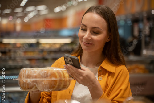 Photography A woman in a yellow jacket picks up various donuts from a display in a grocery store