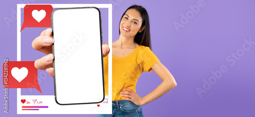 Obraz na plátně An influencer stands against a solid purple background, holding a smartphone with a blank screen