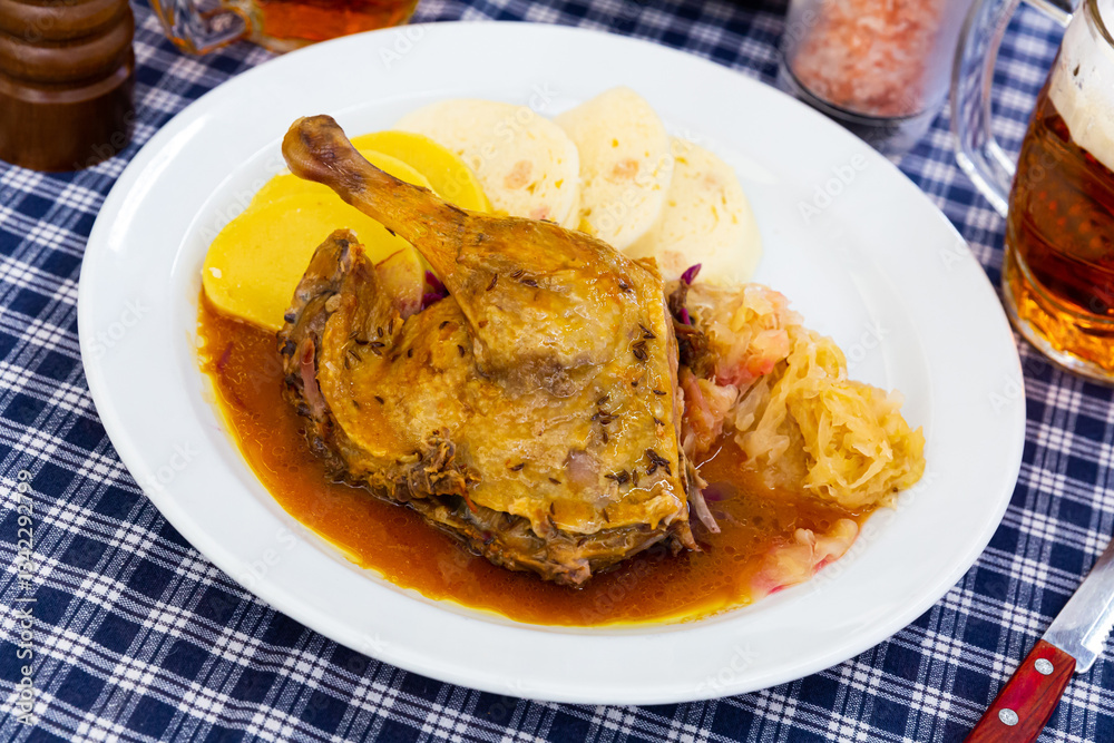 Juicy roasted duck leg served with red and white cabbage and Czech dumplings on plate Juicy roasted duck leg served with red and white cabbage and Czech dumplings on plate