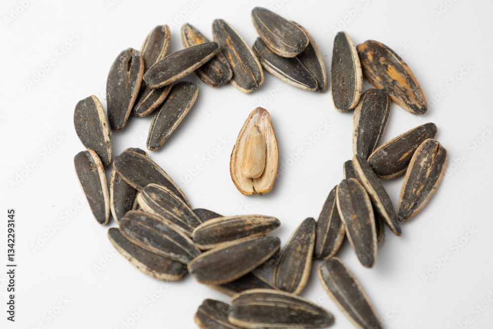 Sunflower seeds forming a circle around a single peeled seed on white background Sunflower seeds forming a circle around a single peeled seed on white background