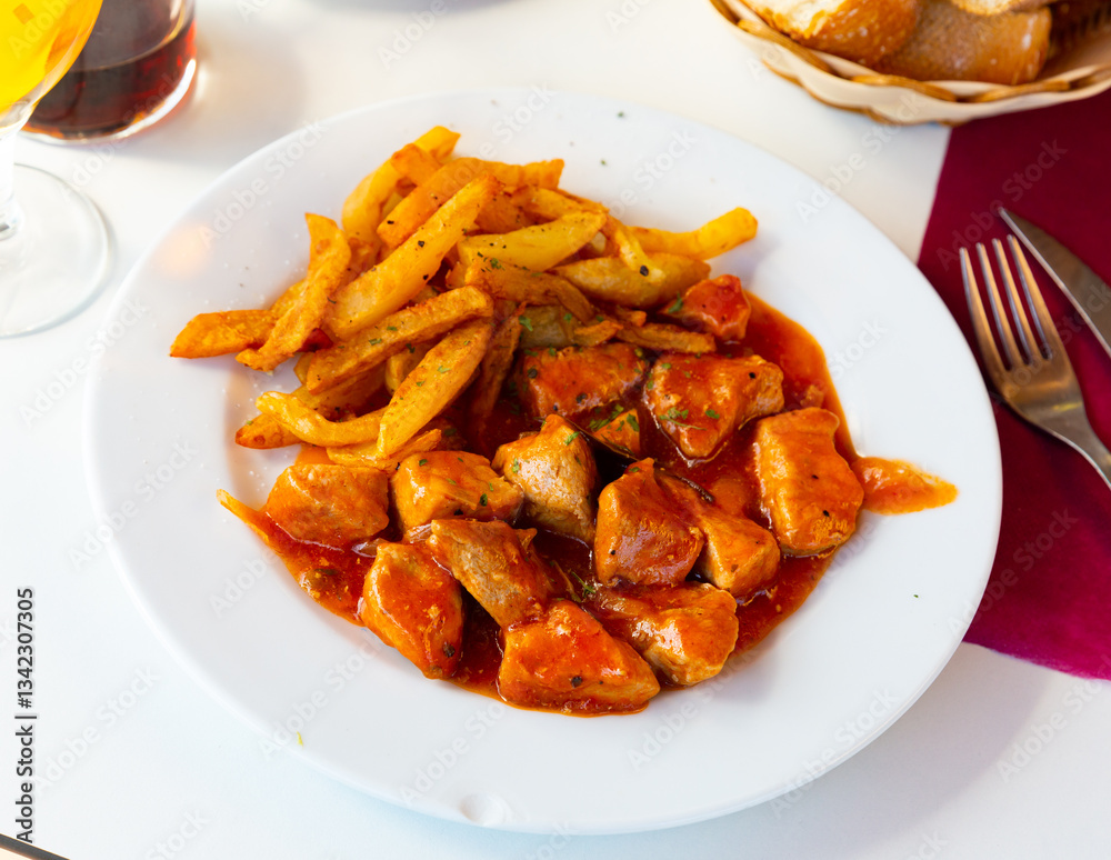 Delicious stewed pork in tomato sauce served on plate with potatoe Delicious stewed pork in tomato sauce served on plate with potatoe