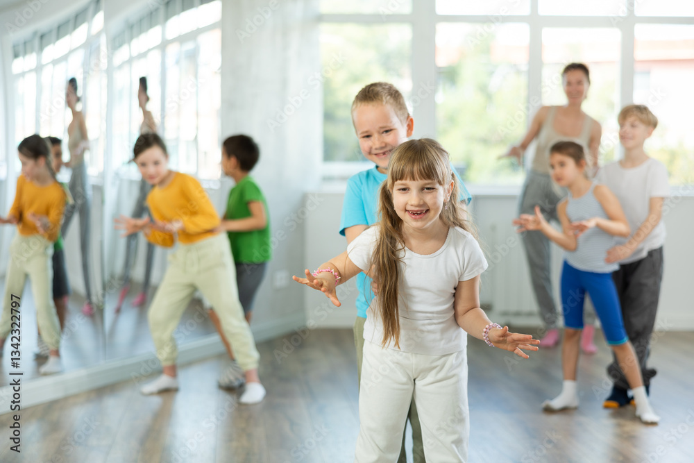 Group of children training movements of twist in dance studio with female tutor Group of children training movements of twist in dance studio with female tutor