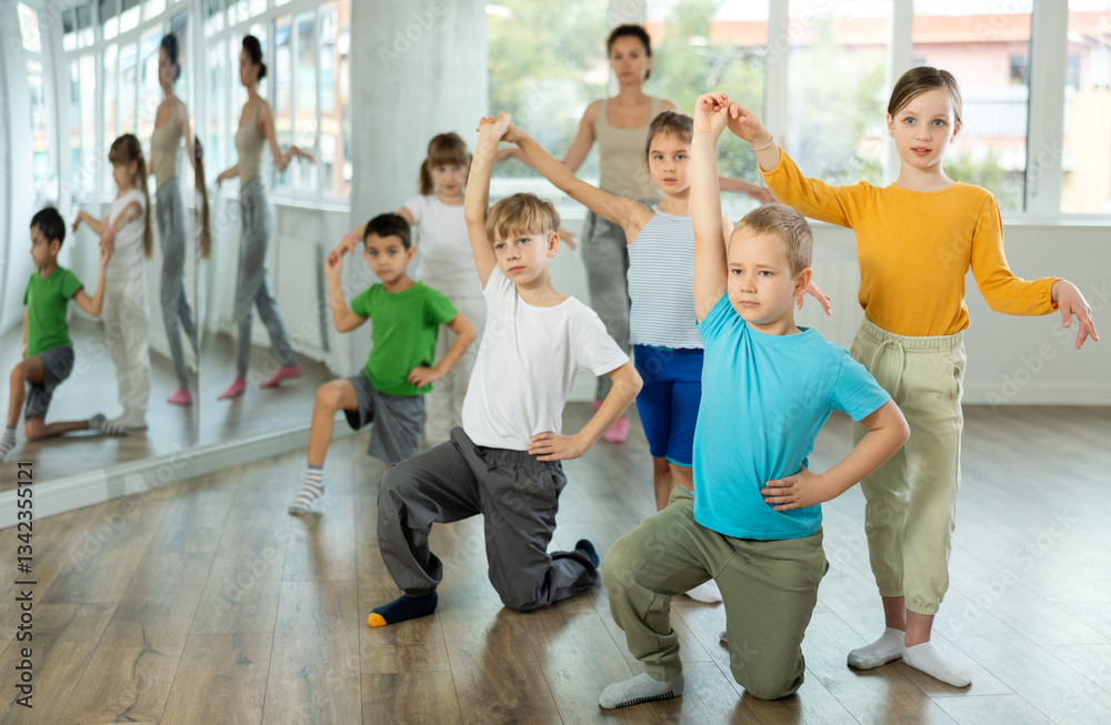 Fototapeta premium Positive juvenile boy and girl doing ballroom dance in pair in training room during workout session