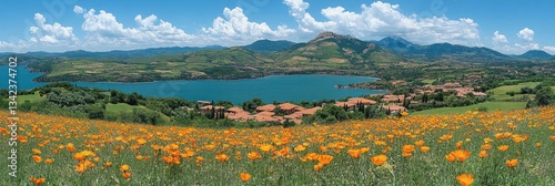 Panoramic view of a lake surrounded by mountains, with a field of wildflowers