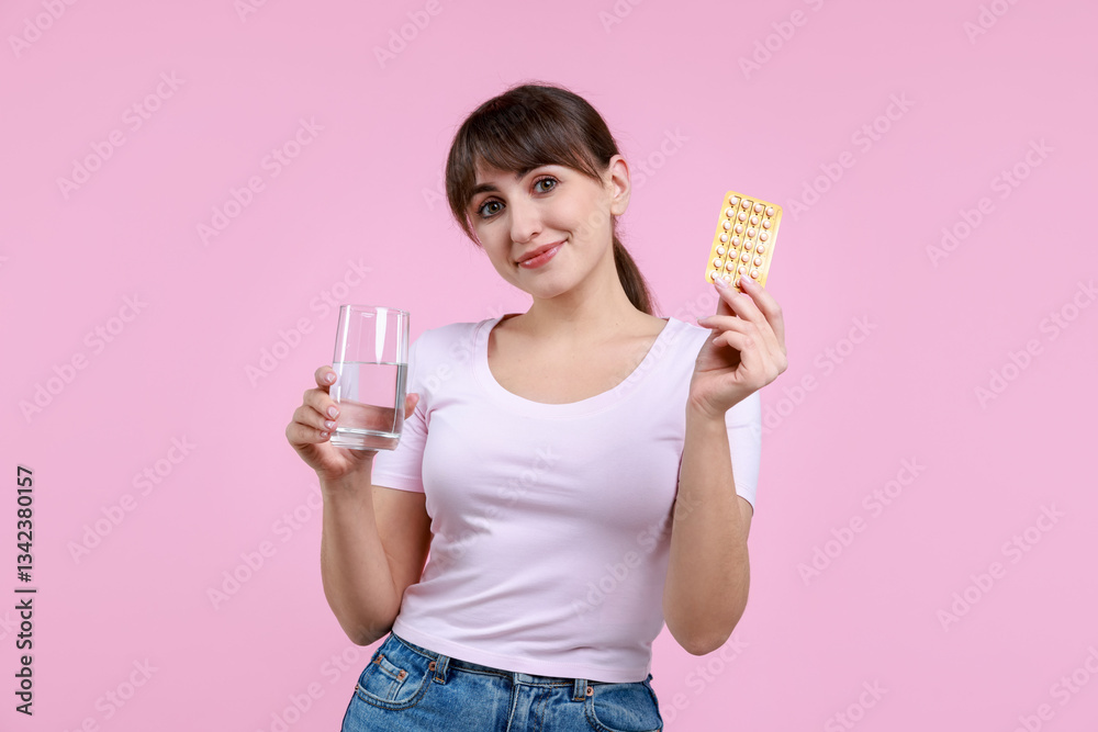 Young woman with contraceptive pills and glass of water on pink background Young woman with contraceptive pills and glass of water on pink background