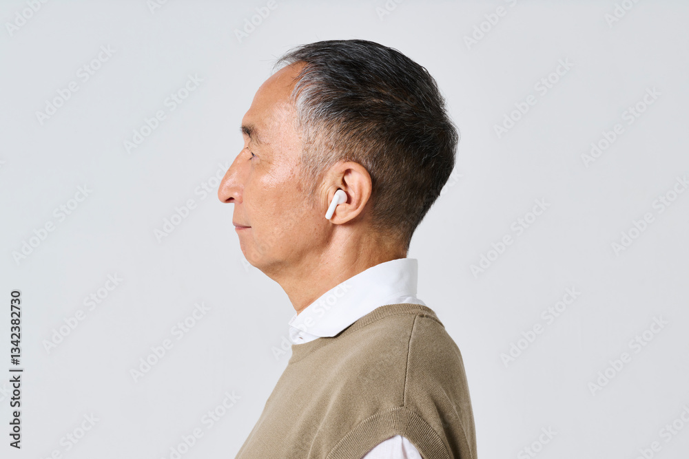 Fototapeta premium ワイヤレスイヤホンを使う私服姿のシニア男性