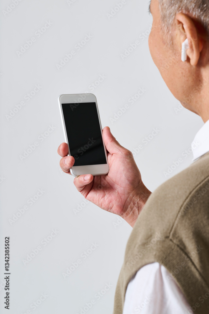 スマートフォンを使う私服姿のシニア男性の後ろ姿 スマートフォンを使う私服姿のシニア男性の後ろ姿